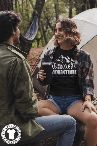 Woman Sitting at camp site with her friend wearing flannel shirt over black t-shirt with "Choose Adventure" design on the front, Available from the Xpert Apparel Store.