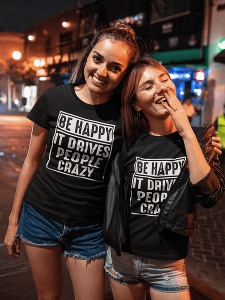 Two Female best friends out at night wearing "Be happy It drives people crazy design available from the Xpert Apparel Store