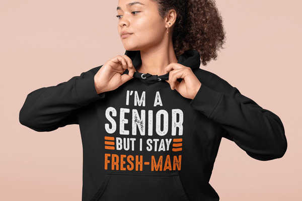 Girl fixing her collar  wearing black Hoodie wearing I'm a Senior But I Stay Fresh-man T-shirt design from the Xpert Apparel Store
