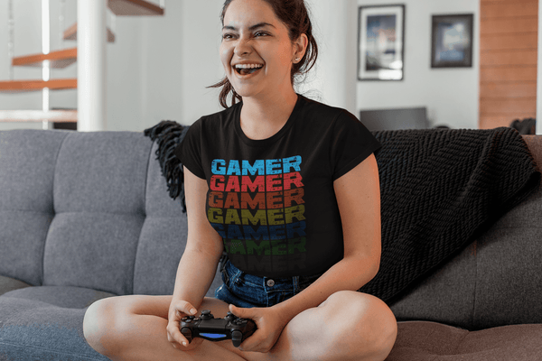 Female Sitting On her  couch playing video games wearing Black T-shirt with Faded out Gamer Design from the Xpert Apparel Store 